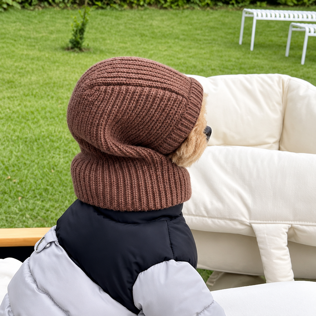 Side view of a small dog wearing a brown knitted head cover outdoors