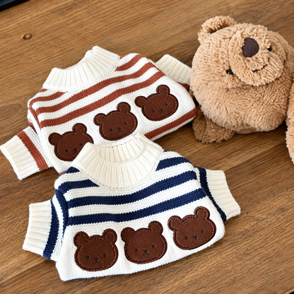 Cream dog jumpers with brown and navy stripes and bear-face motifs beside a teddy bear